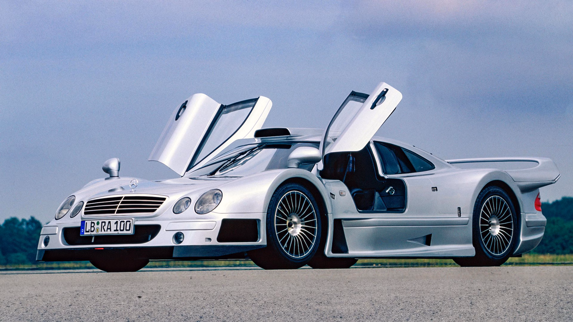 Mercedes-Benz CLK GTR plateado con puertas de ala de gaviota abiertas, ultra exclusivo hypercar de homologación GT1 adquirido por Alonso.