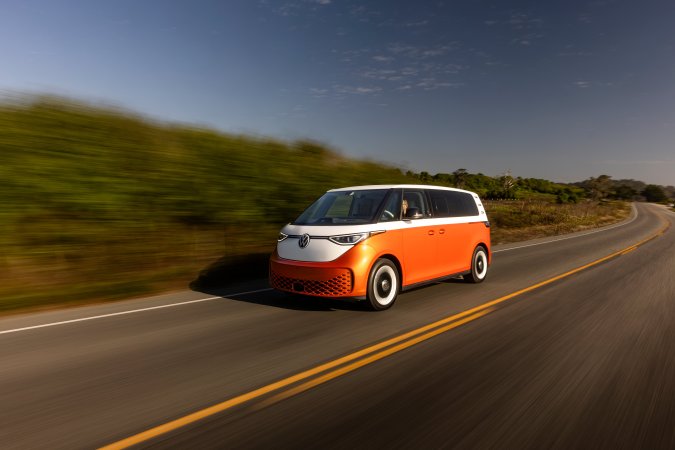 Volkswagen ID. Buzz eléctrico color naranja energético circulando en carretera, mostrando su diseño retro moderno y rendimiento dinámico en movimiento.