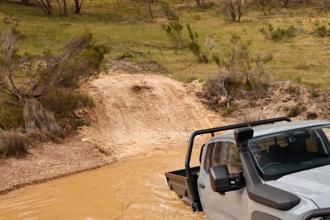 Ford Ranger Super Duty Double Cab gris cruzando terreno con agua y barro, pickup todoterreno de carga pesada, perfecta para trabajo extremo.
