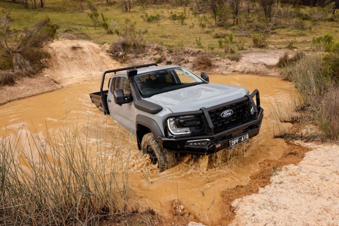 Ford Ranger Super Duty Double Cab gris cruzando terreno con agua y barro, pickup todoterreno de carga pesada, perfecta para trabajo extremo.