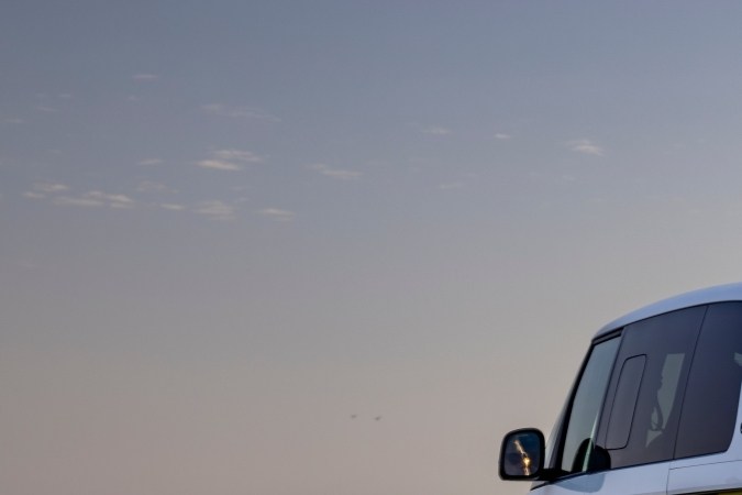 Vista posterior del Volkswagen ID. Buzz amarillo circulando por la costa, exhibiendo su diseño icónico y luces LED traseras en un entorno natural.