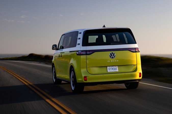 Vista posterior del Volkswagen ID. Buzz amarillo circulando por la costa, exhibiendo su diseño icónico y luces LED traseras en un entorno natural.