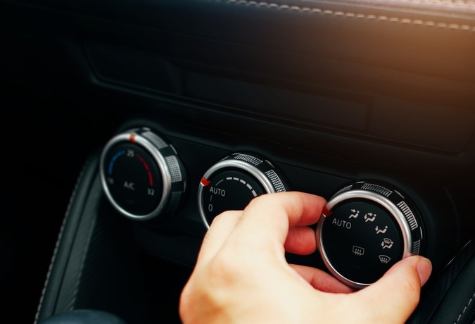 La mano del conductor ajusta el interruptor de dirección del viento en un salpicadero de aire acondicionado del coche, interruptor del botón de giro de un aire acondicionado del coche en un control del panel de interruptores, concepto de tecnología de aire acondicionado del coche.