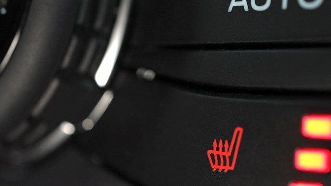 Interruptores calefactables del asiento del automóvil empujados por el conductor para controlar los calentadores de asientos. Primer plano de Botón en el panel del coche para el calor del asiento de coche. Sistema de Vacantes de calor de Clima frío del vehículo.