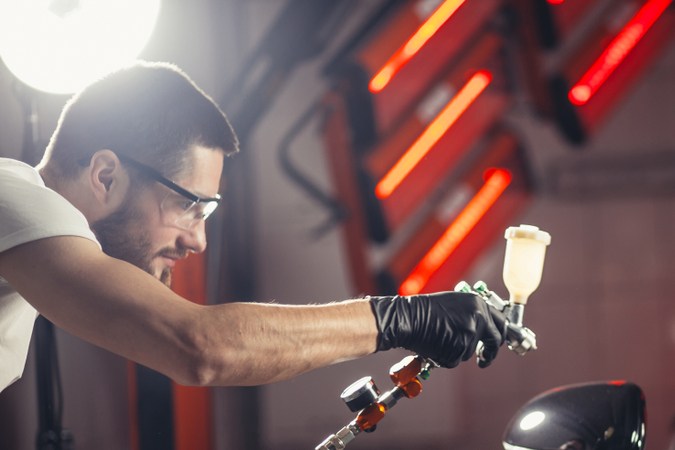 Persona pintando profesionalmente carro de color negro