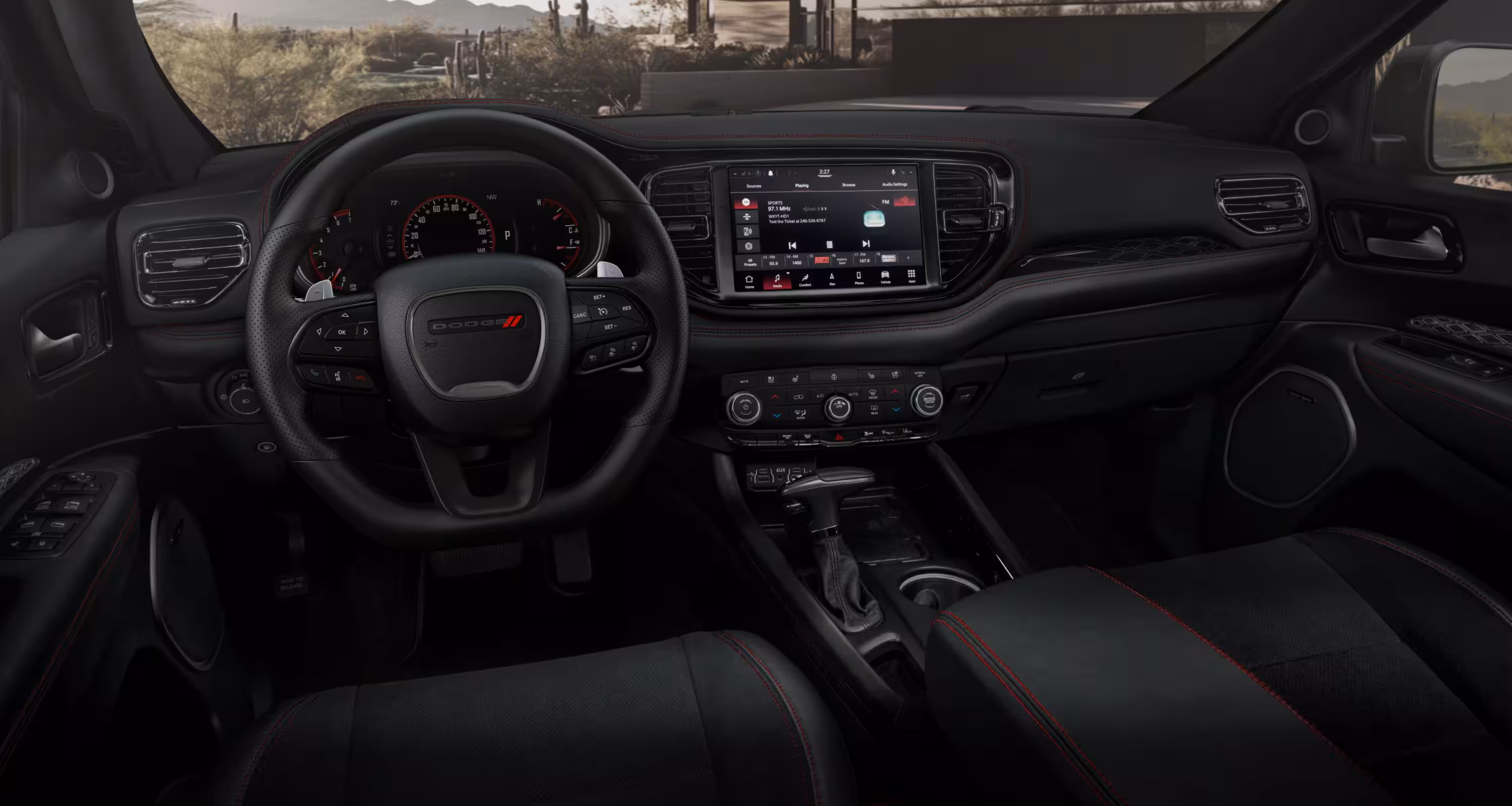 Interior de Dodge Durango SRT Hellcat 2026 mostrando volante deportivo de cuero y panel de instrumentos con sistema de infoentretenimiento Uconnect.