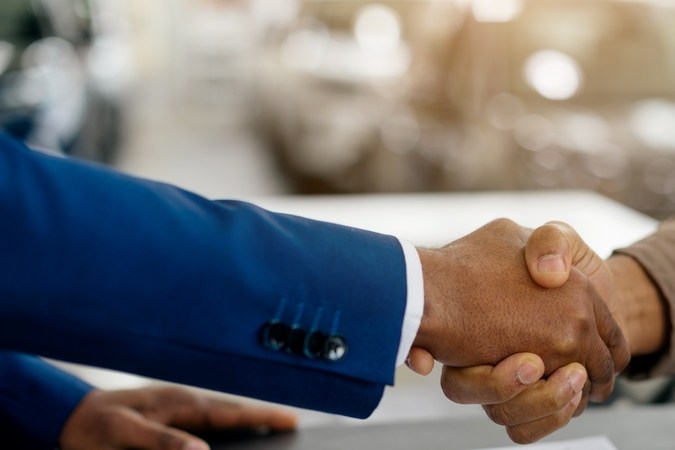 Comprador De Coches Y Vendedor De Automóviles Temblando Las Manos Comprando Automóviles En La Tienda De Concesionarios De Lujo. En gran plano.