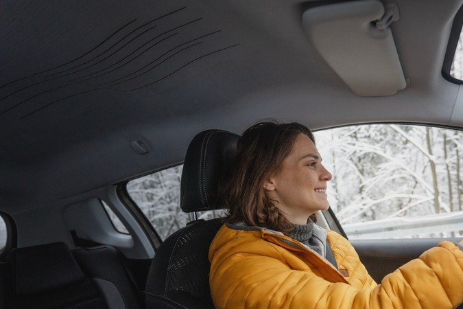 Joven caucásica feliz conduciendo auto en invierno en el bosque, retrato