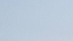 Kia K4 2025 sedán eléctrico gris en estacionamiento con skyline urbano al atardecer, diseño elegante y moderno