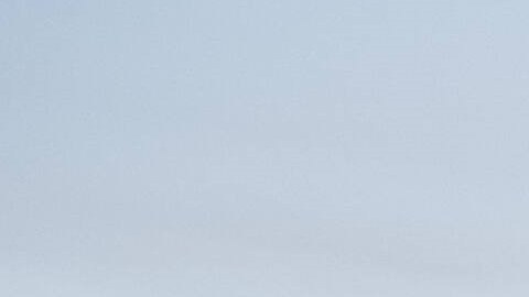 Kia K4 2025 sedán eléctrico gris en estacionamiento con skyline urbano al atardecer, diseño elegante y moderno