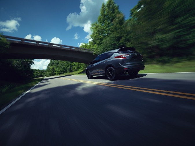 Acura RDX 2025 en carretera boscosa, acelerando con diseño deportivo y elegante