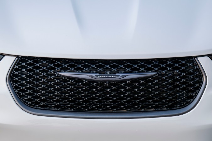 Primer plano parrilla y logo Chrysler Pacifica 2026 blanca, estilo audaz para minivan electrificable.