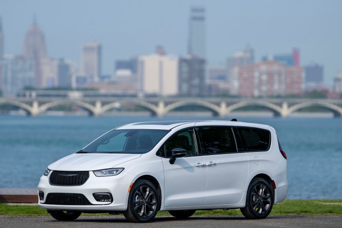 Chrysler Pacifica 2026 blanca frente a skyline y agua, minivan versátil para familias urbanas.