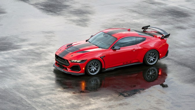 Shelby Super Snake 2026 rojo brillante con capó ventilado y escape Borla, reflejado en pista, listo para humillar al Mustang GTD.