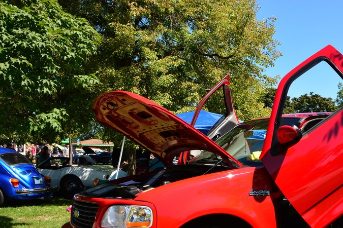 Iluminación Ford de segunda generación con puertas verticales personalizadas. Rojo Brigth con puertas y capó abiertos en una exposición local de coches aparcada en el césped.