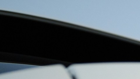 Detalle trasero Genesis GV80 blanco al atardecer, logotipo iluminado, luces LED encendidas, SUV de lujo coreano, imagen enfocada en diseño y elegancia.