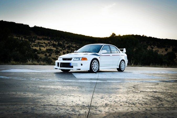 Vista del Mitsubishi Lancer evolution VI tommi makinen edición limitada blanca en helipuerto al atardecer
