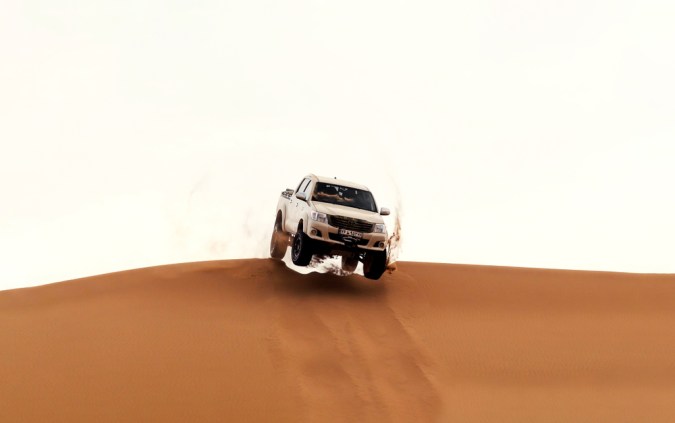 Toyota Hilux 2021 salta desde la cima de una duna de arena en el desierto del Sahara o Dasht e Lut
