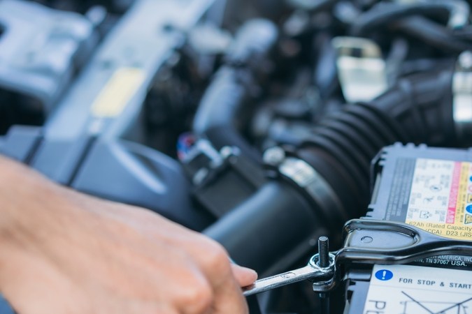Un hombre mantiene su auto, revisa y cambia la batería. Concepto de mantenimiento de coches.