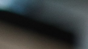 Imagen de mano masculina en guante negro protector, sosteniendo esponja con cera sólida de carnauba, y puliendo capucha de auto amarillo de lujo en taller de detalles profesionales. Detalles del coche.