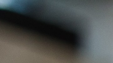 Imagen de mano masculina en guante negro protector, sosteniendo esponja con cera sólida de carnauba, y puliendo capucha de auto amarillo de lujo en taller de detalles profesionales. Detalles del coche.