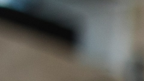 Imagen de mano masculina en guante negro protector, sosteniendo esponja con cera sólida de carnauba, y puliendo capucha de auto amarillo de lujo en taller de detalles profesionales. Detalles del coche.