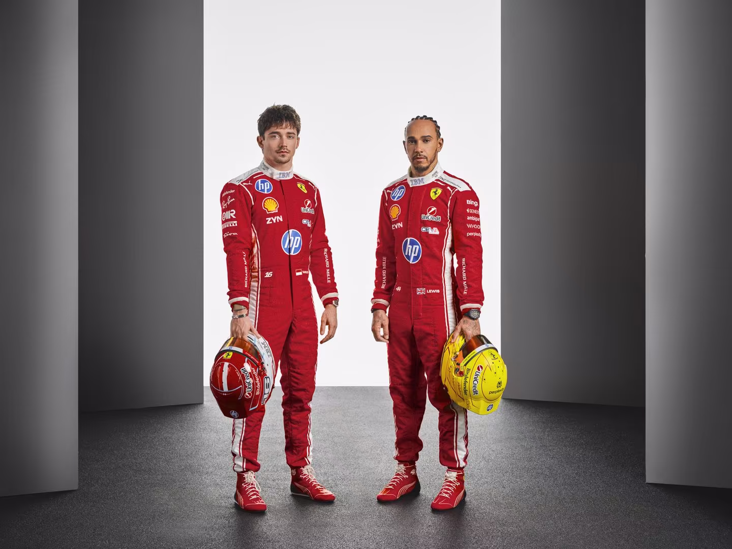 Charles Leclerc y Lewis Hamilton pilotos Ferrari 2026, trajes rojos con cascos para temporada F1.