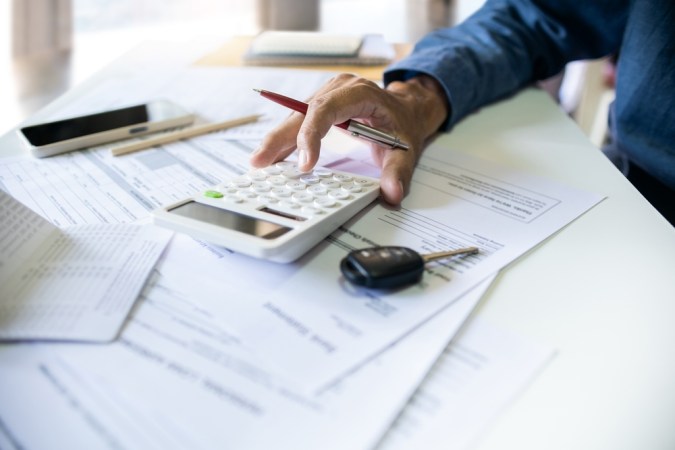 La mano de los hombres calcula las cuotas mensuales y comprueba el pasaporte y el extracto bancario antes de solicitar préstamos de coche para resolver problemas financieros en los negocios