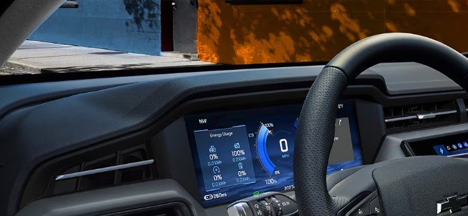 Interior moderno Chevy Bolt 2027 con pantallas digitales y volante ergonómico para conductor.