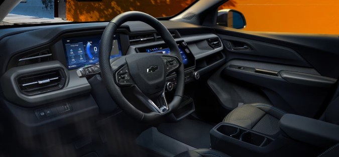Interior moderno Chevy Bolt 2027 con pantallas digitales y volante ergonómico para conductor.