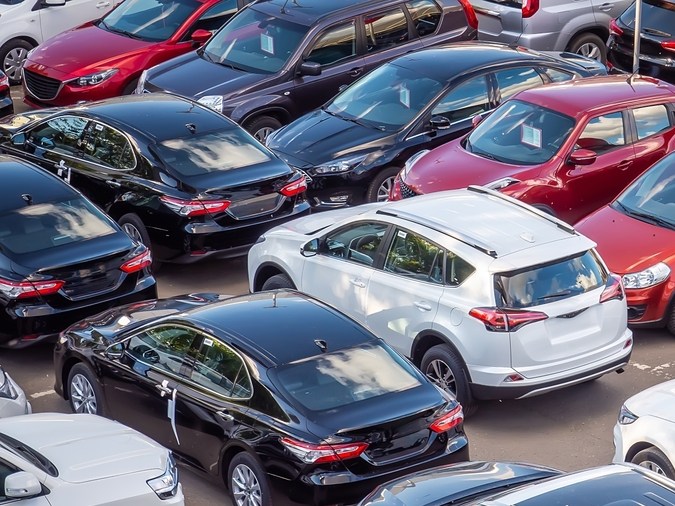 Venta de coches nuevos y usados en un concesionario. Hay muchos coches en el aparcamiento. Automóviles negros, blancos, plateados y rojos de marcas desconocidas