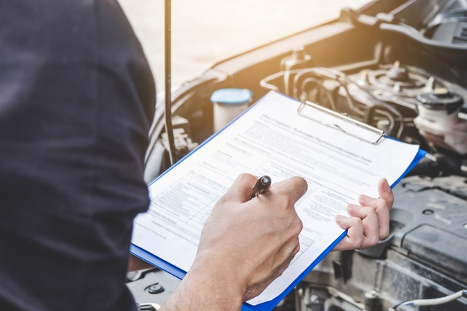 El concepto de máquina de camión de servicios, reparador mecánico de automóviles revisando un motor de camión inspeccionando la escritura en el portapapeles de la lista de comprobación de la máquina de reparación, servicio de camión y mantenimiento.