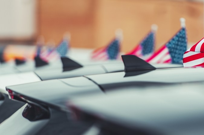 Fila autos deportivos subasta EE.UU. Subaru WRX blanco, VW Beetle azul, banderas americanas, evento automotriz