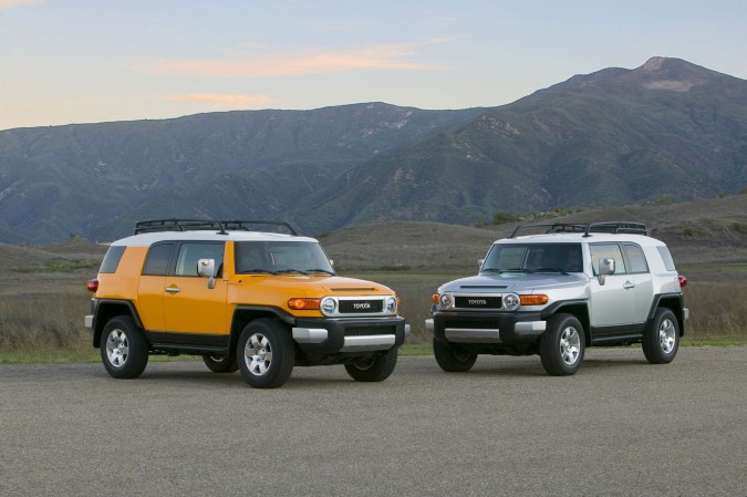 Toyota FJ Cruiser amarillo y plateado en paisaje montañoso al atardecer, SUVs icónicos estilo retro Toyota.