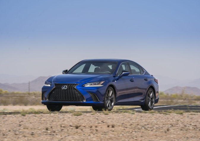 Lexus ES azul en movimiento sobre carretera desértica al atardecer, diseño elegante y deportivo de sedán de lujo japonés