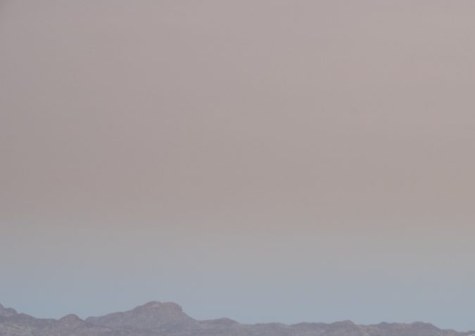 Perfil lateral del Lexus ES azul metálico con llantas deportivas y líneas aerodinámicas, sedán de lujo en entorno desértico