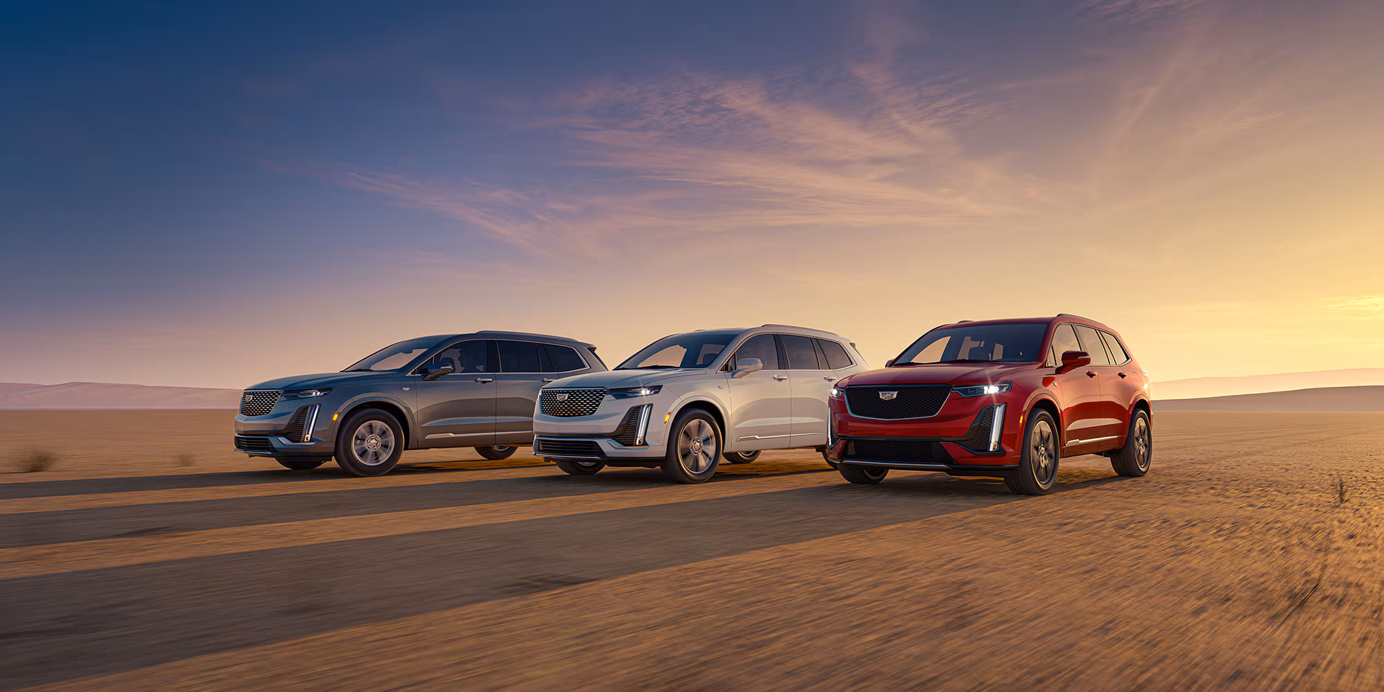 Cadillac XT6 2025 en desierto al atardecer, SUV premium gris plateado y rojo