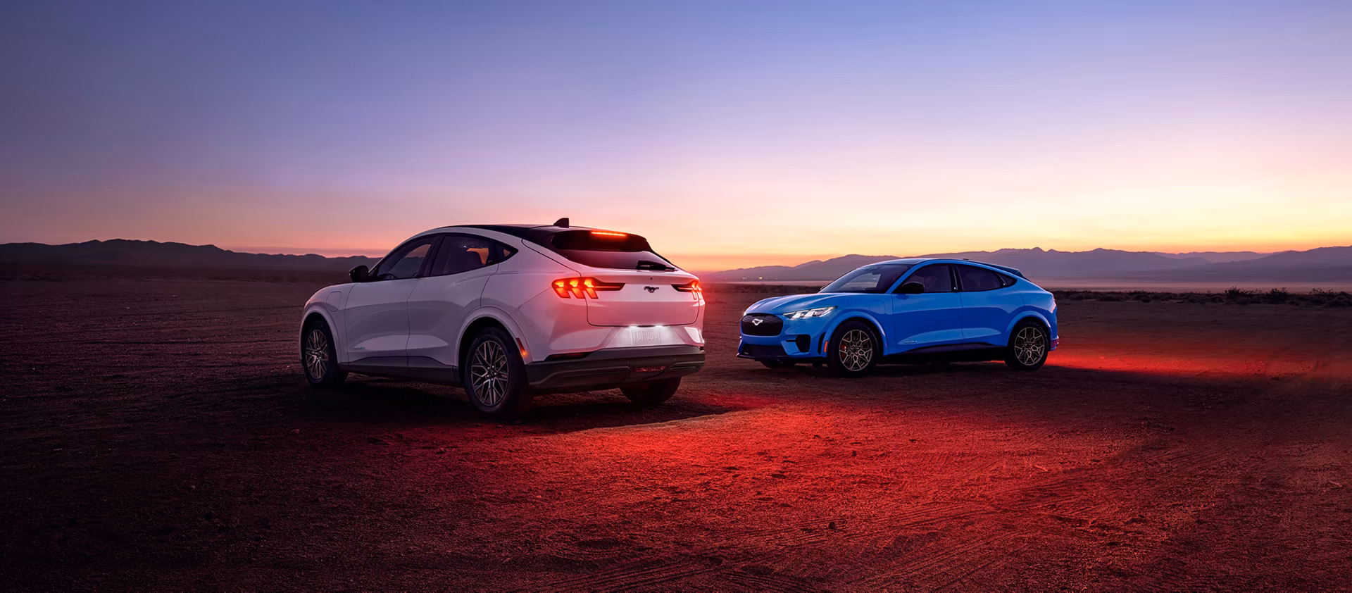 Vista trasera de dos Ford Mustang Mach-E 2026 en desierto al atardecer, destacando diseño SUV eléctrico deportivo.