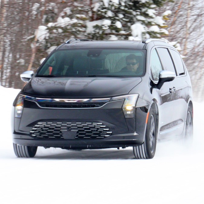 Chrysler Pacifica 2027 circulando en nieve profunda, con faros verticales y parrilla moderna en acción invernal.