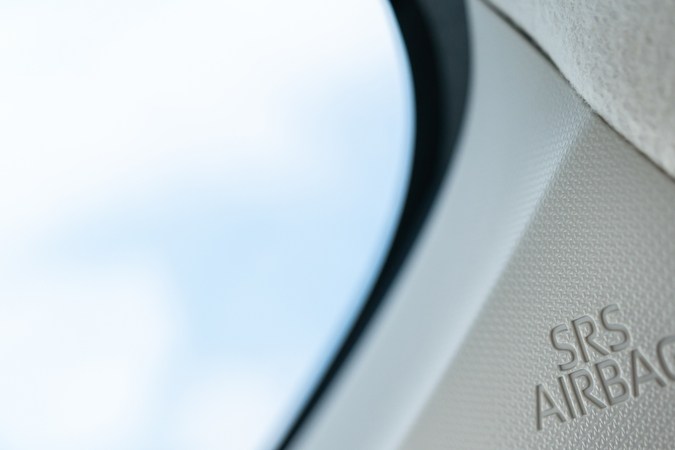 La etiqueta SRS Airbag en el guarnecido interior de un coche, específicamente en el pilar A. Este airbag es parte del sistema de seguridad del automóvil diseñado para desplegarse durante una colisión para proteger a los ocupantes.