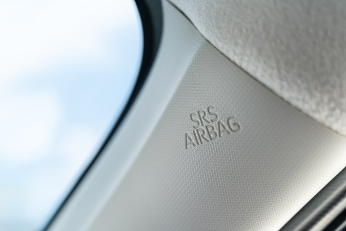 La etiqueta SRS Airbag en el guarnecido interior de un coche, específicamente en el pilar A. Este airbag es parte del sistema de seguridad del automóvil diseñado para desplegarse durante una colisión para proteger a los ocupantes.