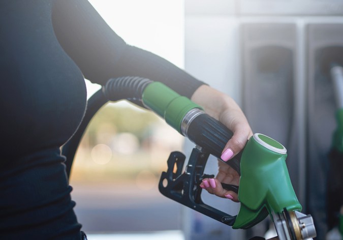 La gentil mano de la mujer está sosteniendo un arma de combustible. El tanque de la motocicleta está alimentado por la propietaria.