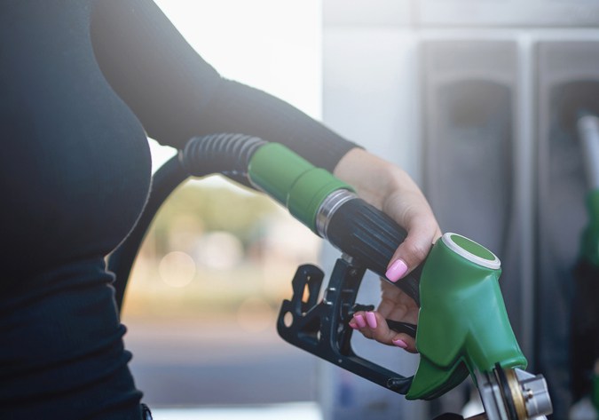 La gentil mano de la mujer está sosteniendo un arma de combustible. El tanque de la motocicleta está alimentado por la propietaria.