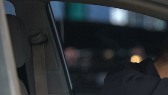 Conductor masculino con supuraciones en el volante, cansado tras el trabajo, riesgo de accidente de coche