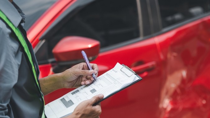 accidentes, automóviles, seguros, automóviles, choques, Reclamos, colisiones. Un inspector registra los detalles de un vehículo rojo con daños laterales después de una colisión, completando un formulario de informe de seguro.