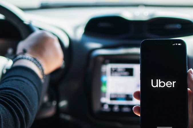 Chica dentro de un auto sosteniendo un smartphone con la aplicación Uber en pantalla