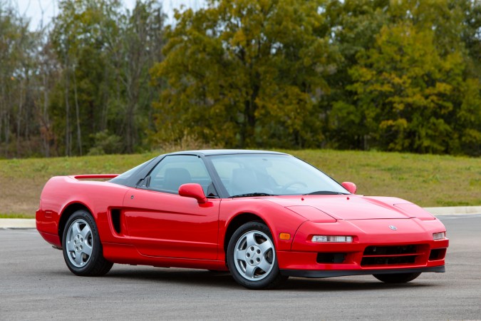 Perfil lateral del Acura NSX clásico rojo 1991 estacionado, puertas alas de murciélago y chasis de aluminio ligero