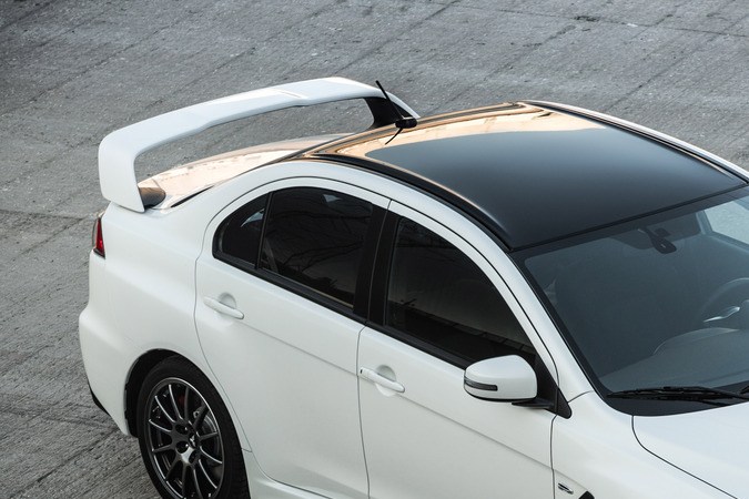 Lancer Evolution 2015 blanco con alerón, vista superior en estacionamiento, auto deportivo Mitsubishi premium.