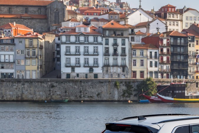 Honda CR-V ePHEV 2023 en color blanco, vista lateral trasera en el puerto de Oporto con fondo de ciudad histórica