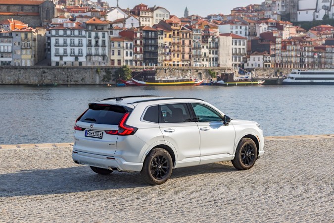 Honda CR-V ePHEV 2023 en color blanco, vista lateral trasera en el puerto de Oporto con fondo de ciudad histórica